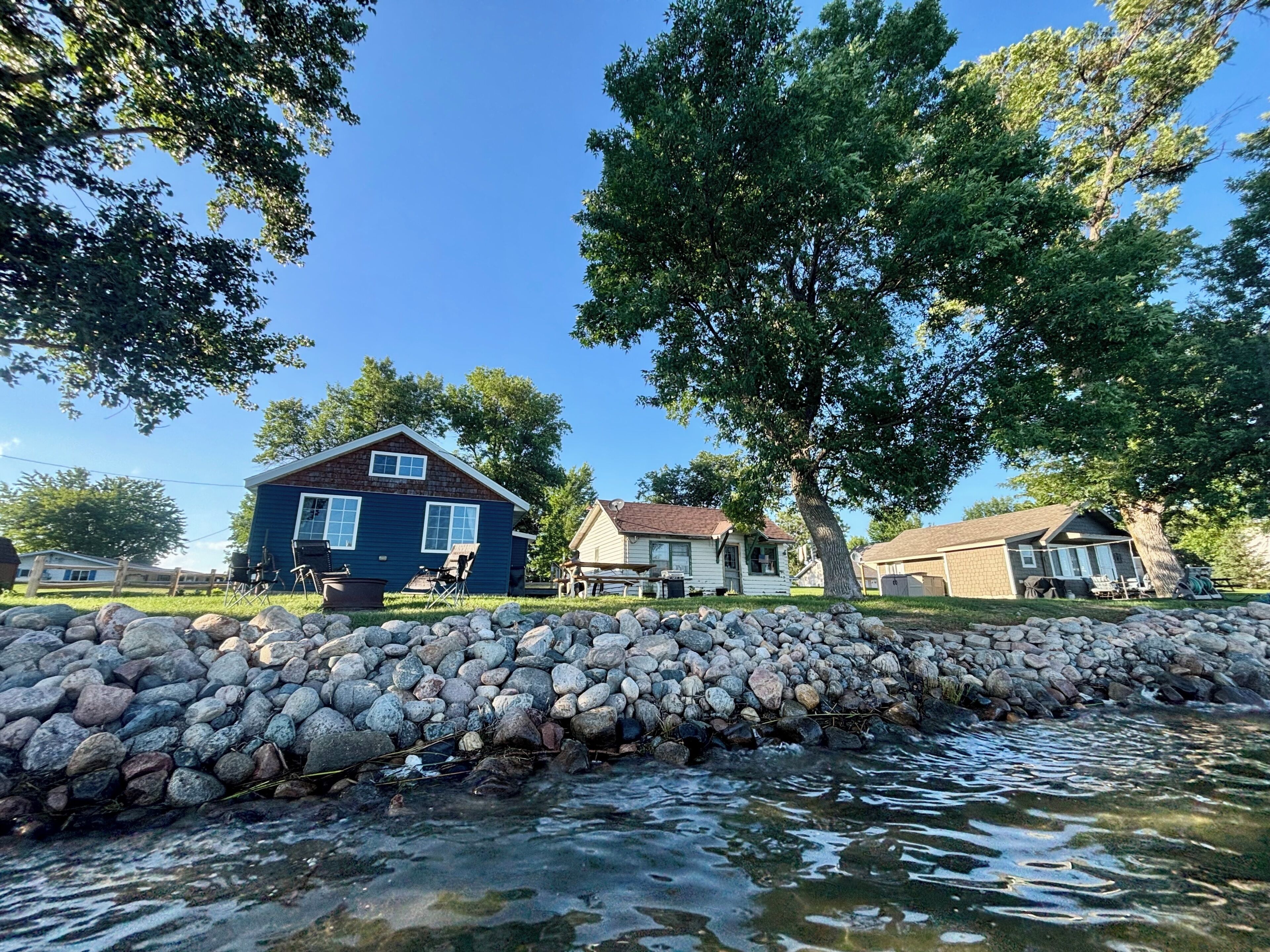 A residential area with houses, a stone wall, and a clear sky.