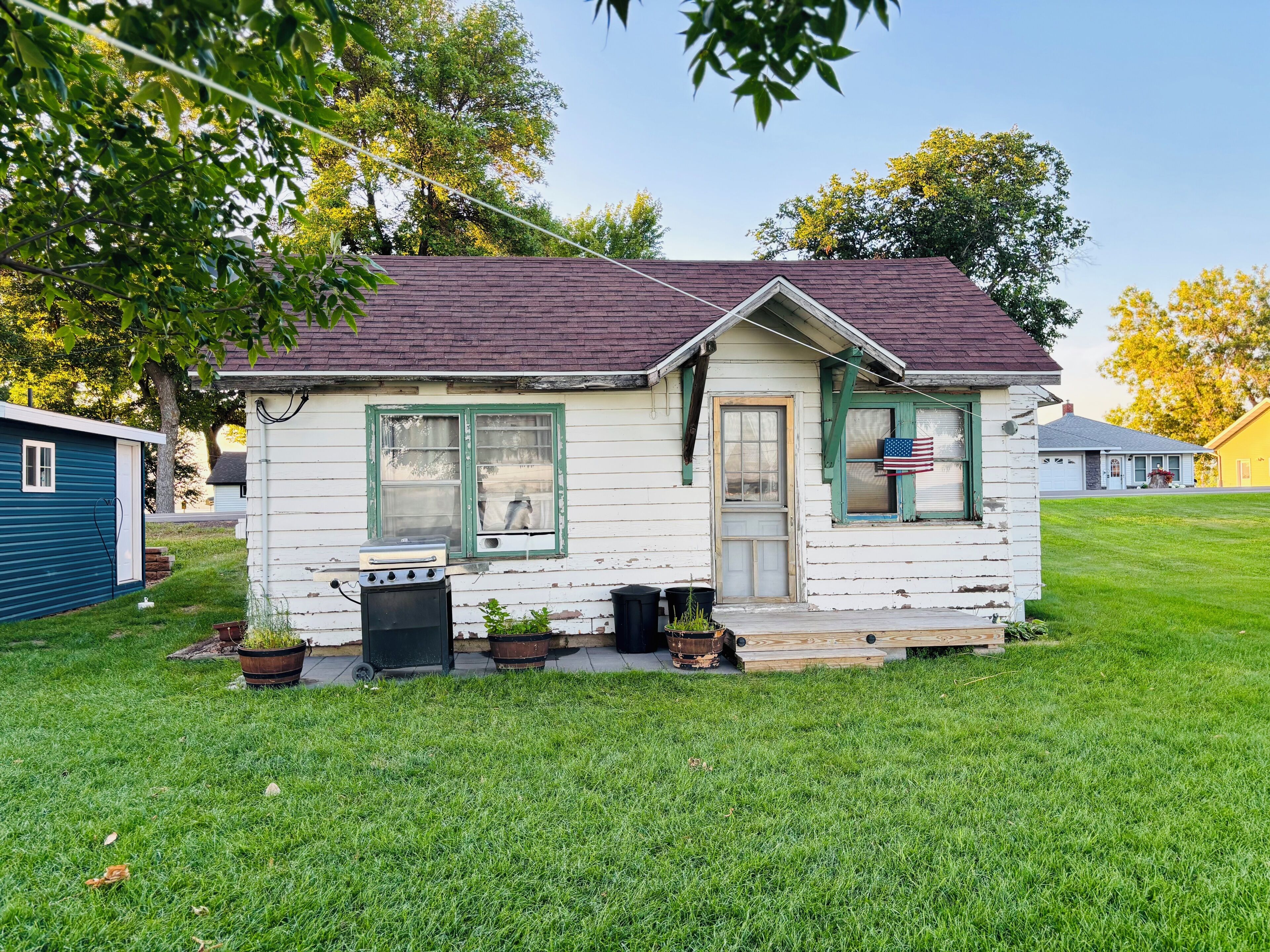 A small, single-story house with a front porch, a garage, and a yard.