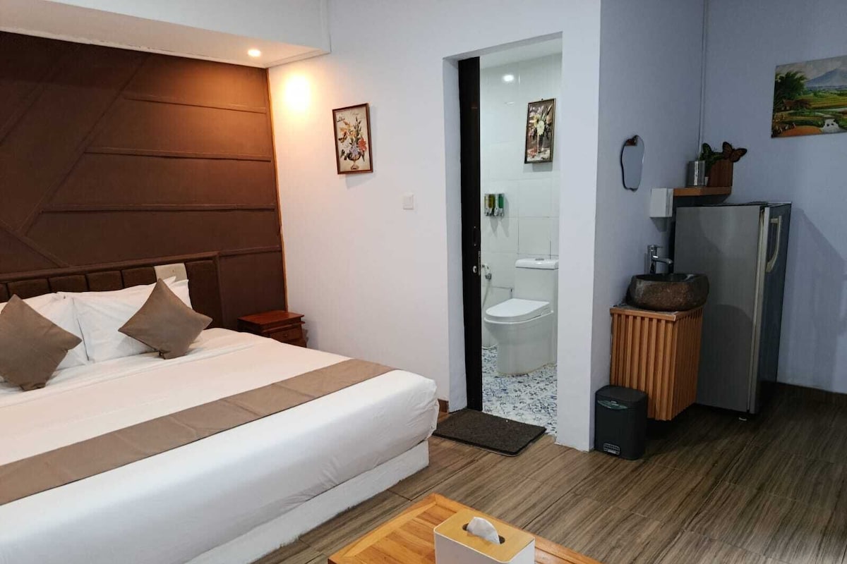 A bedroom with a bed, bedside table, and a small wooden table with a tissue box.