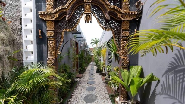 A narrow pathway flanked by ornate metal gates and lush tropical plants. - Sri Asta Guna (Legian)