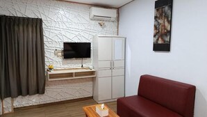A living room with a sofa, a TV, a cabinet, and a wooden table. - Sri Asta Guna (Legian)