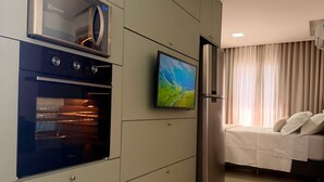 Una cocina moderna con horno, microondas integrado y televisor de pantalla plana.