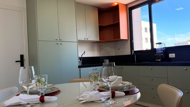Una cocina moderna con una mesa de comedor para dos, un ventanal con vistas y armarios de colores claros.