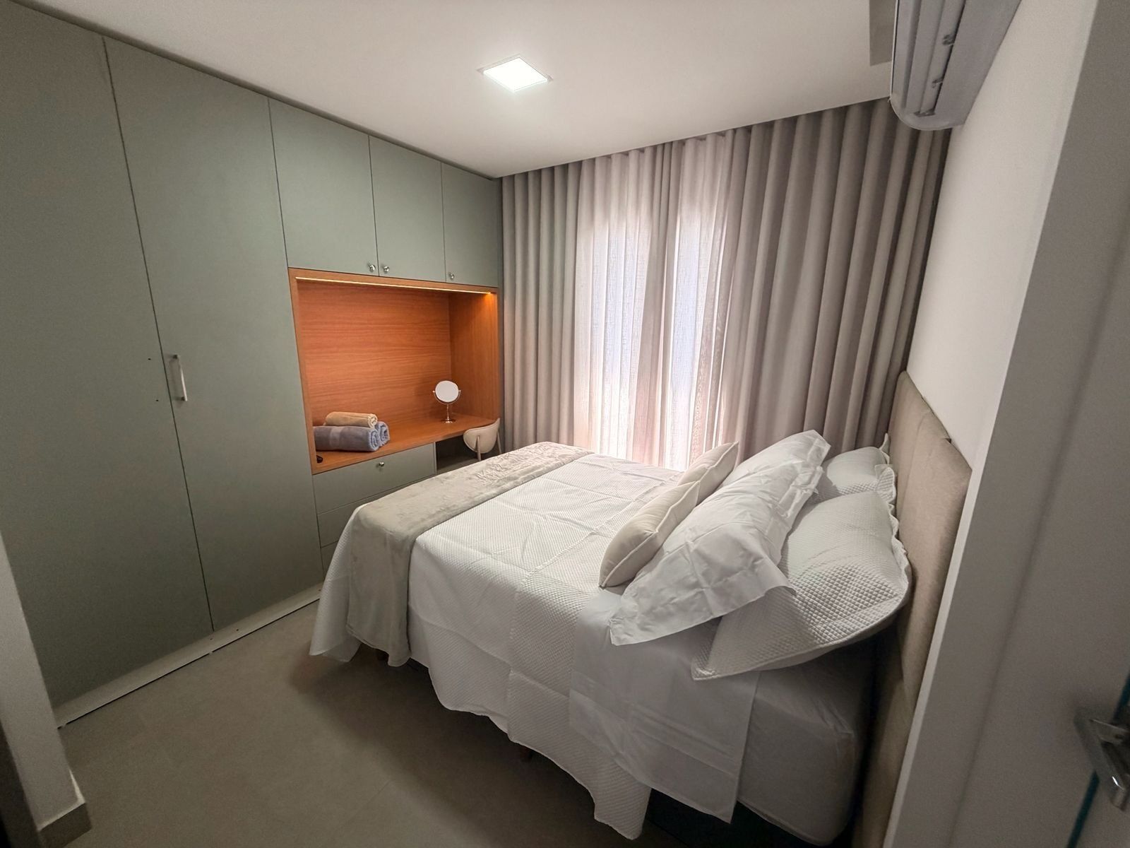 Una habitación de hotel con una cama, un armario, una tocador con espejo y una ventana con cortinas.
