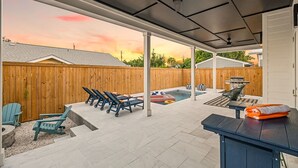 Eine überdachte Terrasse mit Pool, Liegestühlen und einem Tisch.