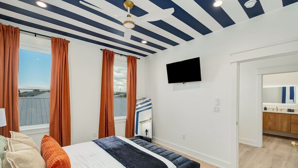 Een slaapkamer met een bed, een bankje, een televisie en uitzicht naar buiten.