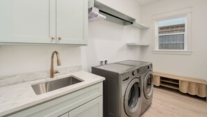 Een moderne keuken met een spoelbak, kasten en een ingebouwde wasmachine en droger.