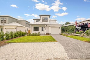 A residential house with a driveway, a lawn, and a garage. - NEW! Walk to Beach, Pool, Game Room, Lux Retreat (Panama City Beach)