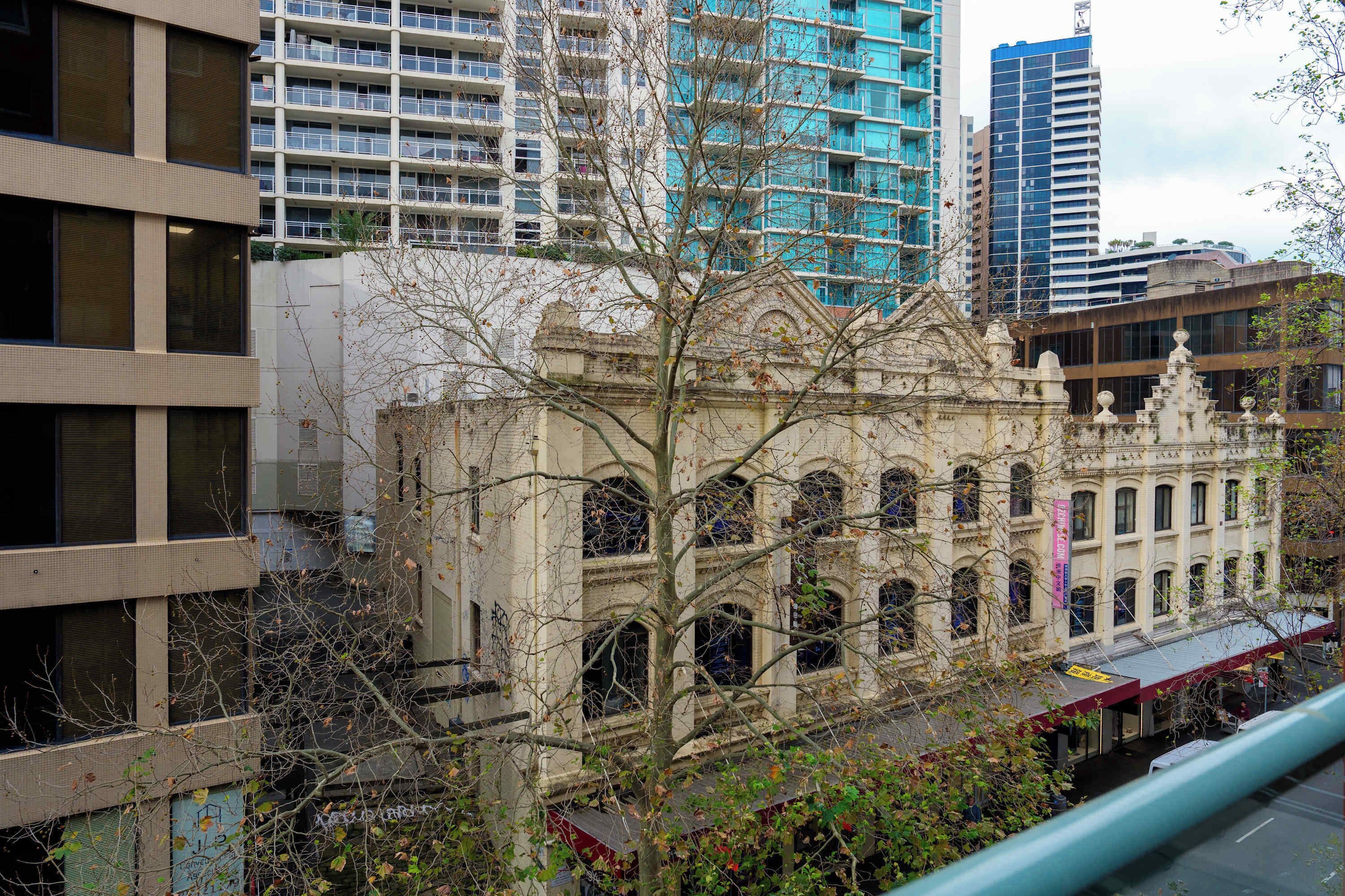 A historic building with arched windows and a central dome, surrounded by modern high-rise buildings.