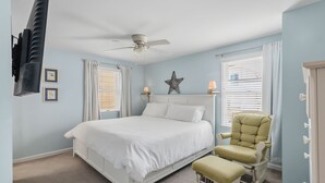 A bedroom with a bed, a chair, a ceiling fan, and a star decoration on the wall. - Ocean City NJ Beach Block 5BR/2.5BA - Steps to Beach (Ocean City)