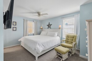 Ein Schlafzimmer mit einem Bett, einem Sessel, einem Deckenventilator und einer Sternenverzierung an der Wand.