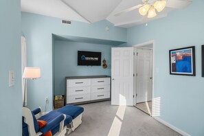 A room with a television on the wall, a desk with drawers, a chair, a door, and a framed picture. - Ocean City NJ Beach Block 5BR/2.5BA - Steps to Beach (Ocean City)