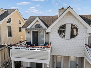 A residential building with a balcony, a garage, and a distinctive fish-scale roof design. - Ocean City NJ Beach Block 5BR/2.5BA - Steps to Beach (Ocean City)