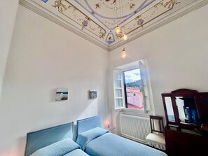 Ein Schlafzimmer mit Bett, Fenster mit Blick, Heizkörper und Spiegel.