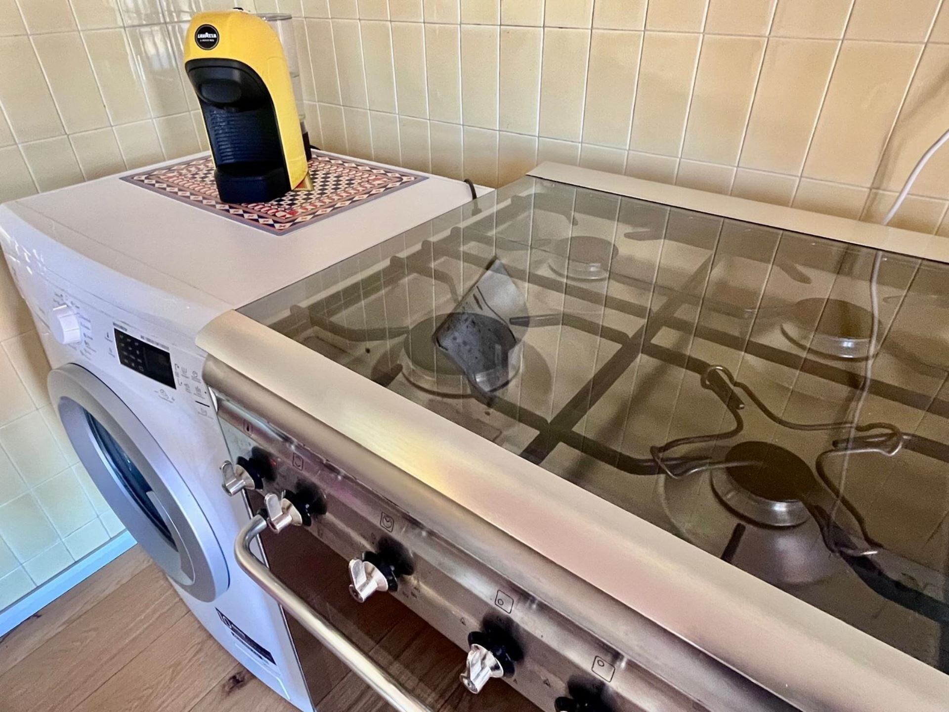 Keittiössä on kaasuliesi, pesukone ja keltainen kodinkone työtasolla.