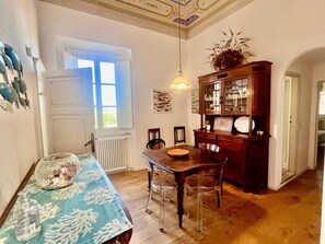 Ein Essbereich mit einem Holztisch, klaren Stühlen, einer blauen Tischdecke und einem Schrank mit Glastüren.