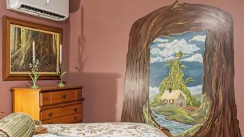 A bedroom with a bed, dresser, and a painting of a forest scene.