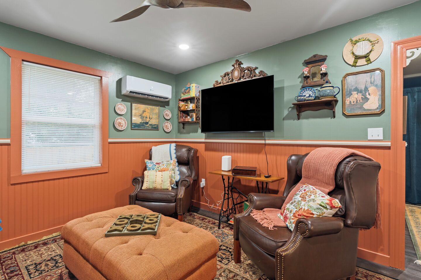 A living room with a television, two leather chairs, a coffee table, and a patterned rug.