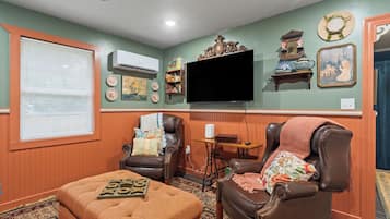 A living room with a television, two leather chairs, a coffee table, and a patterned rug.