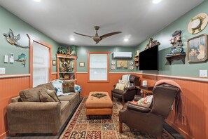 A cozy living room with a fireplace, comfortable seating, and decorative wall art. - Storybook Cottage Near Downtown Hattiesburg-Family Friendly (Hattiesburg)