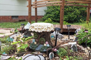 A garden with a mushroom-shaped table, fairy doors, and lanterns.