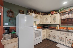 Eine Küche mit einem weißen Kühlschrank, einem Herd und Küchenschränken mit Blumenmuster.
