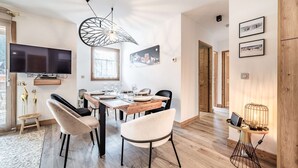 Et moderne spiseområde med et træbord, stole og et fjernsyn ophængt på væggen.