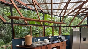 A rustic kitchen with a stone floor, wooden cabinets, and a stainless steel refrigerator. - Beautiful 2 Story Dome Perfect for Your Getaway (Rivas)