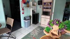 A room with a dining table, chairs, a small refrigerator, a cabinet, and a decorative plant arrangement. - Doña Lucía (Guánica)
