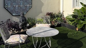 A patio with a metal table and chairs, a decorative wall, and a swan sculpture. - Room-cozy Studio Retreat in Saint Albans (Melbourne)