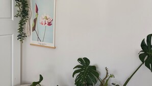 A corner of a room with a white wall, a macrame plant hanger, a framed botanical illustration, and several potted plants. - Room-cozy Studio Retreat in Saint Albans (Melbourne)