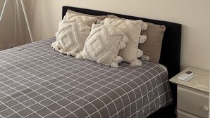 A bedroom with a bed, bedside table, lamp, and an air conditioning unit. - Room-cozy Studio Retreat in Saint Albans (Melbourne)