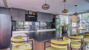 Una cucina moderna con isola centrale, sgabelli da bar e luci a sospensione.