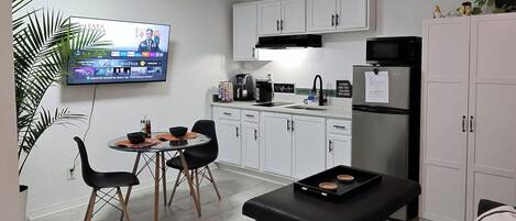 A compact living space with a dining area, kitchenette, and a television mounted on the wall.