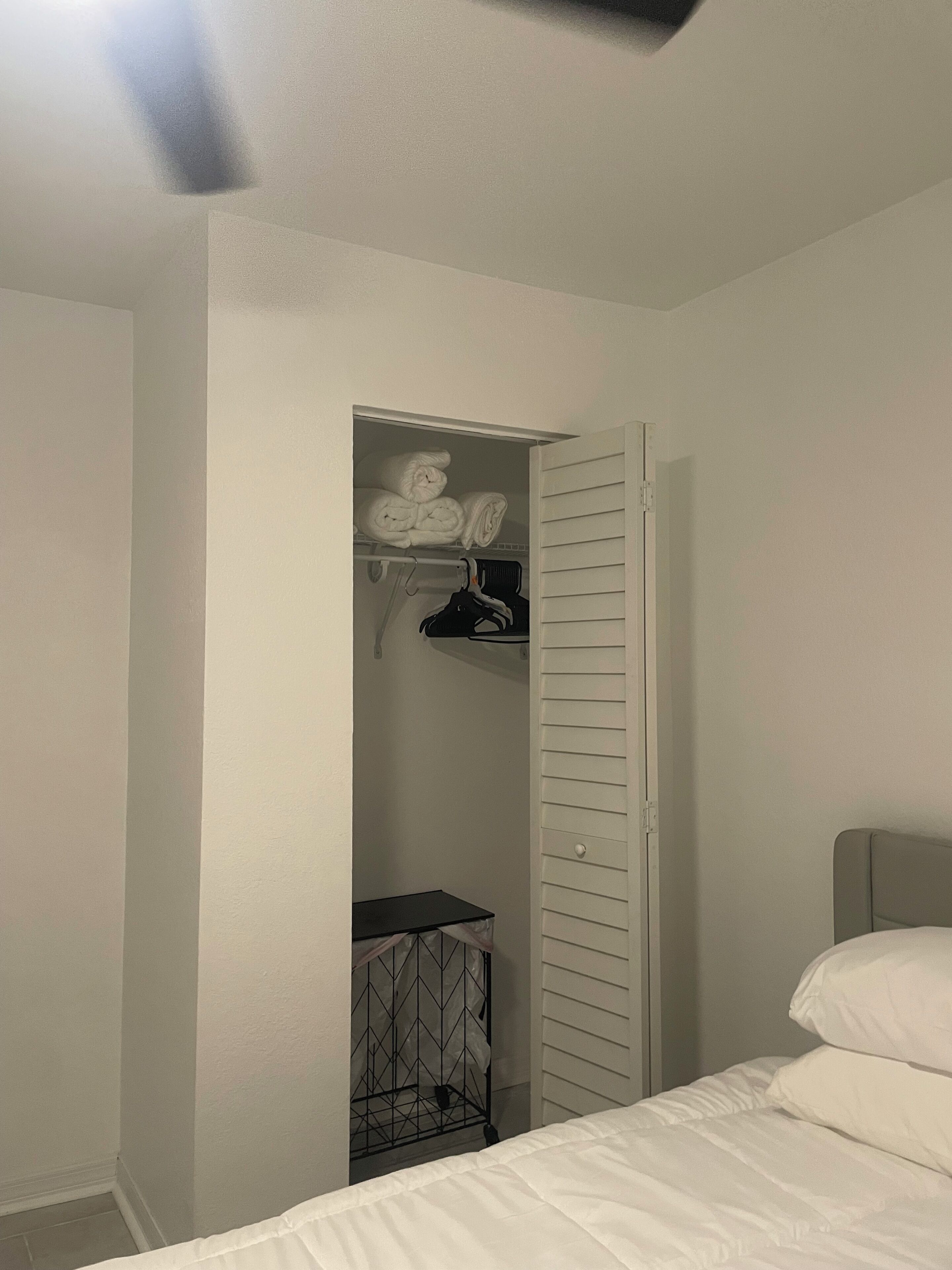 Un dormitorio con cama, armario con espacio para colgar y una mesita.