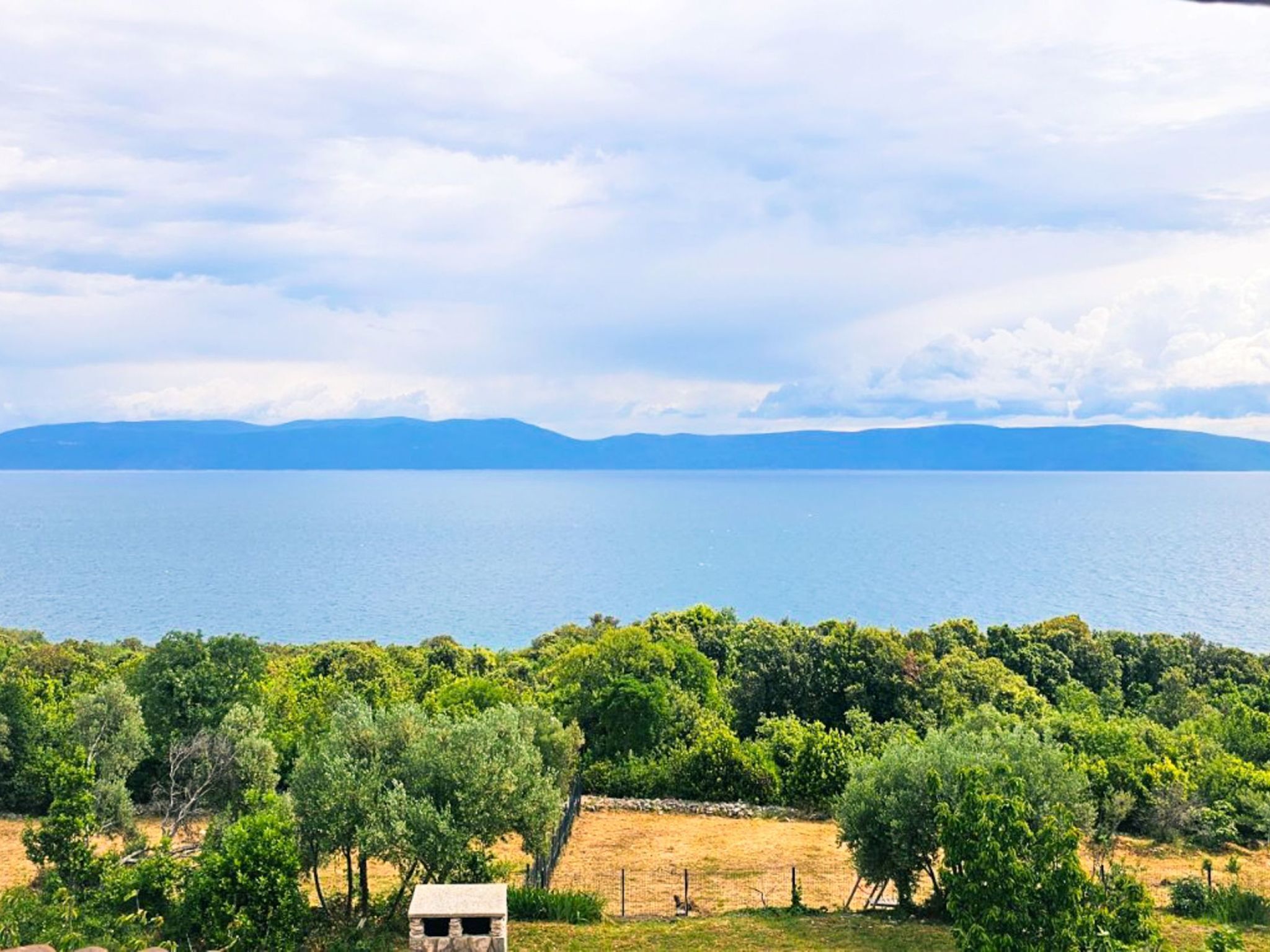 Eine Küstenlandschaft mit freiem Blick auf das Meer und entfernte Berge.