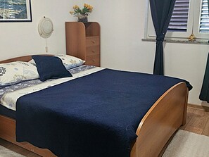 A bedroom with a bed, a dresser, a window with curtains, and a wall-mounted fan. - Valerija by Interhome (Labin)