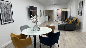 A modern living room with a round dining table, two chairs, a sofa, and a coffee table.