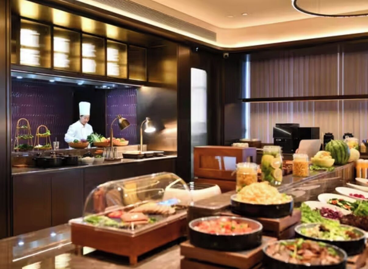 A buffet setup with various food items and a chef in the background.