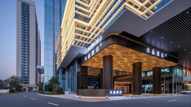 A modern hotel with a prominent entrance, large pillars, and a glass facade.