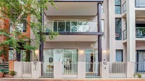 Un edificio de varios pisos con acceso a nivel de calle, un balcón y una escalera visible.