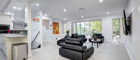 Una sala moderna con un sofá, una mesa de centro y un televisor montado en la pared.