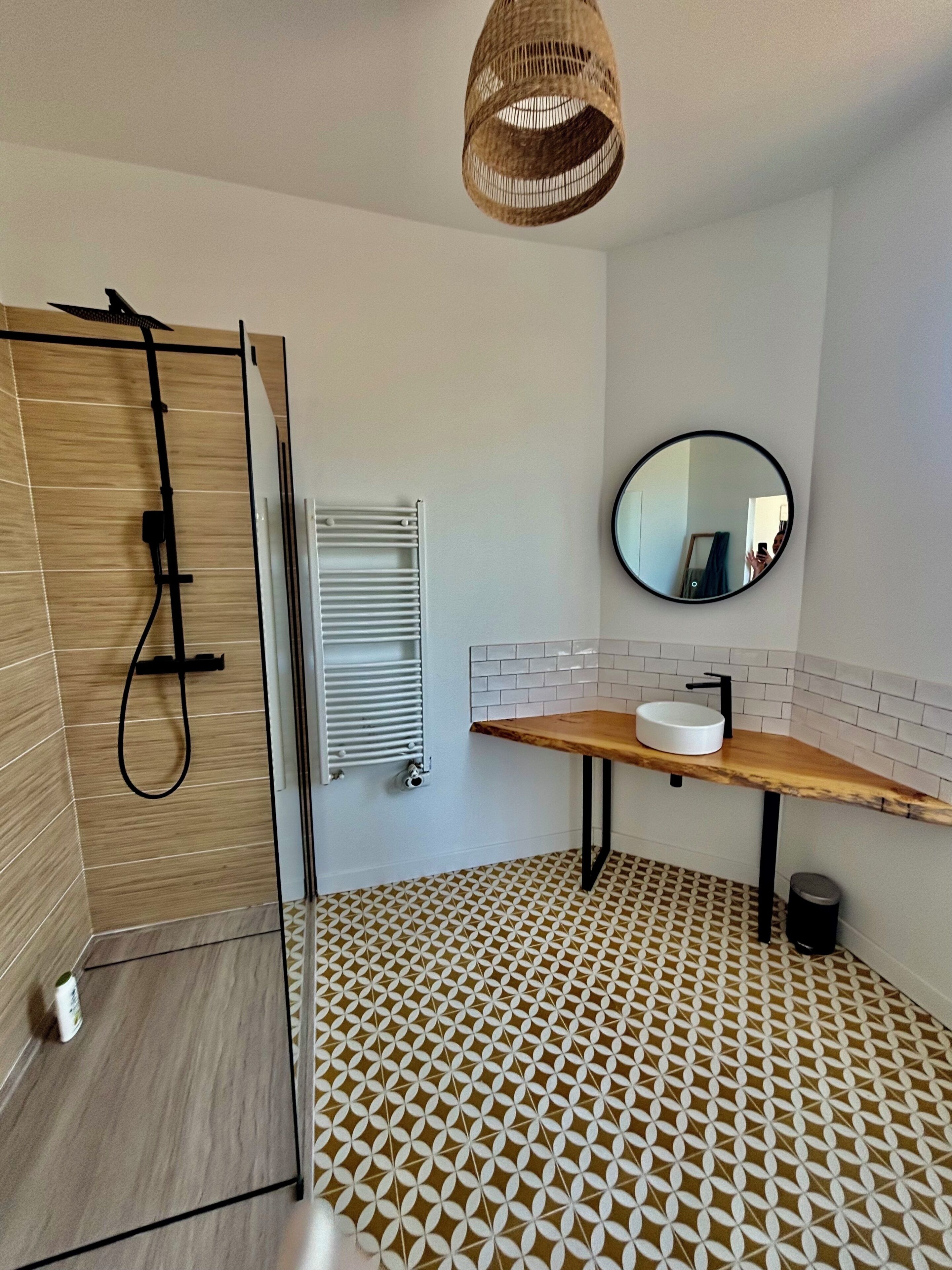 Ein Badezimmer mit Dusche, Waschbecken, Spiegel und einem Musterfußboden.