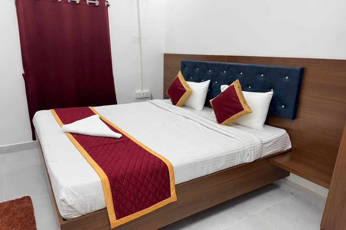 Uma cama com cabeceira de madeira, roupa de cama branca e detalhes em vermelho e dourado.