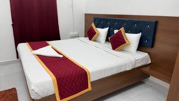 Una cama con cabecera de madera, ropa de cama blanca y detalles en rojo y dorado.