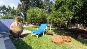 A backyard with a blue lounge chair, a large pot, and a small table. - Nature Villa · Pool · Large Garden · Cap Bon (Grombalia)