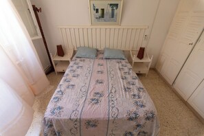 Ein Schlafzimmer mit einem Bett, zwei Nachttischen, einem Spiegel und einer Tür.