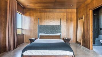 A modern bedroom with a wooden ceiling, a large bed with a headboard, two bedside tables, and a window with curtains.