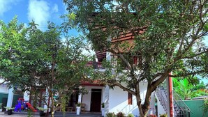 A residential house with a red roof, a staircase, and a small garden with potted plants.