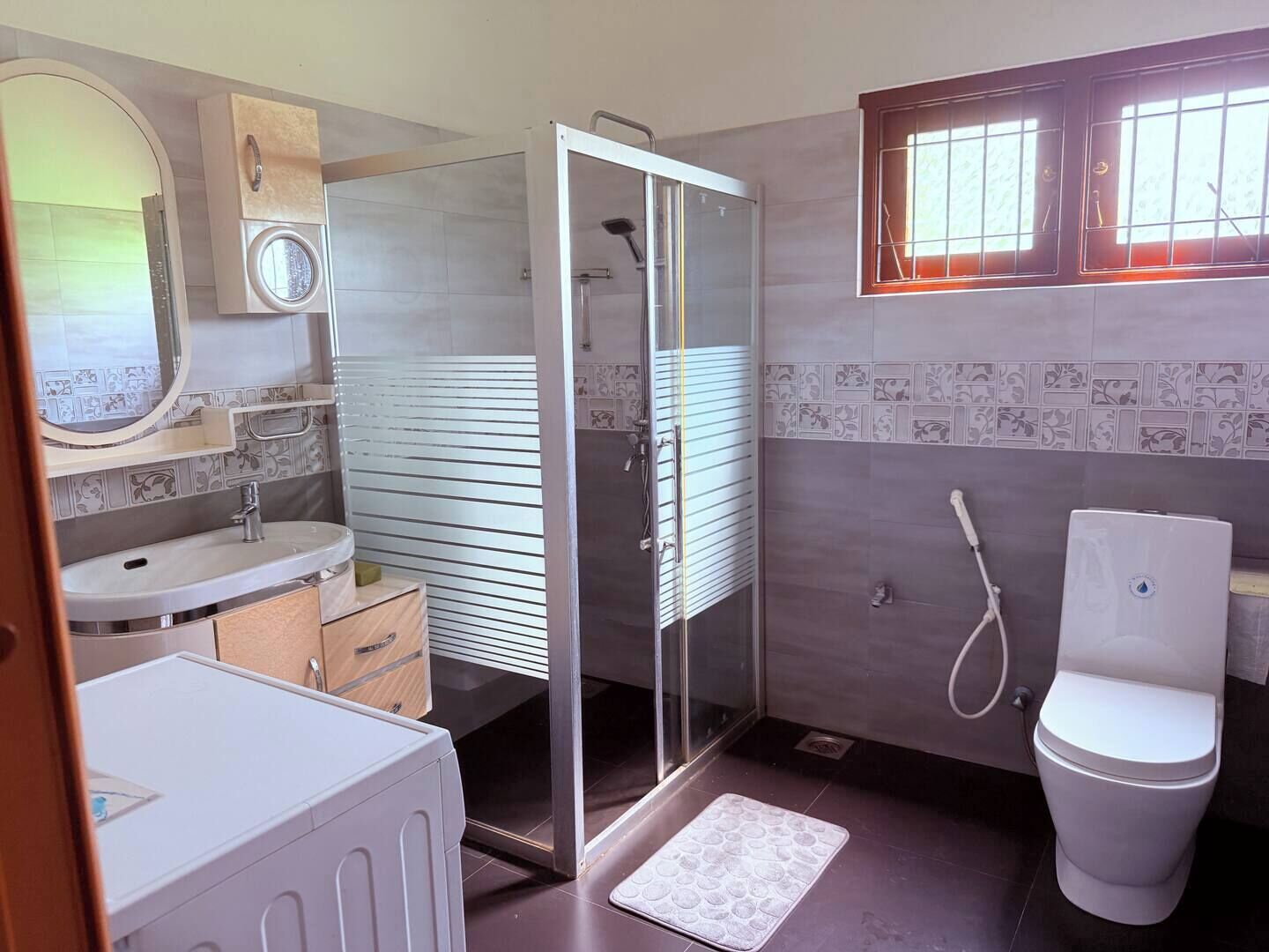 A modern bathroom with a shower, toilet, and sink.